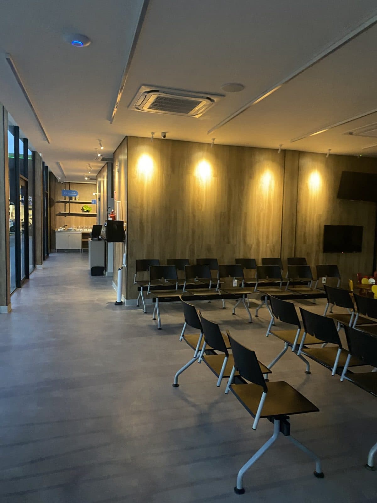 Sala de espera pronta, com painéis amadeirados e luz quente